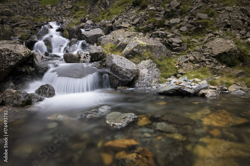 Weird small waterfall in beautiful and rocky scenery with vibrant rocks in the water