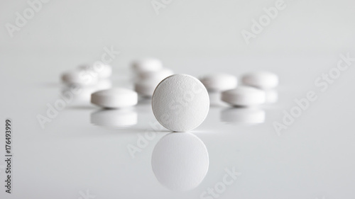 Close up of white round tablets on white background.