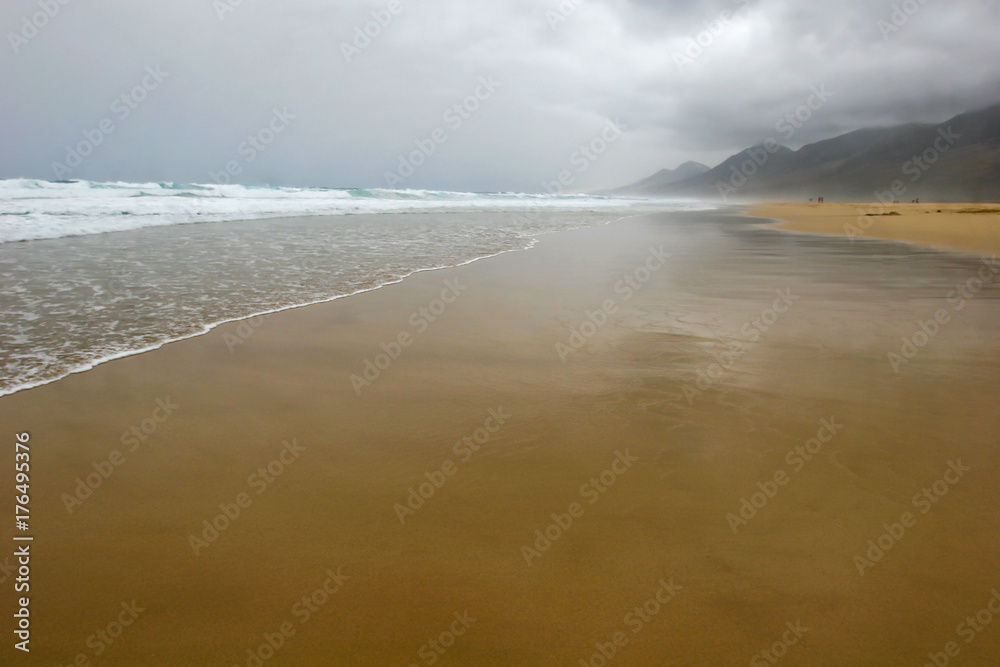 Reflection of mountains in wet sand on Cofete beach in secluded part of Fuerteventura in cloudy weather, Canary Islands, Spain Reflection of mountains in wet sand on Cofete beach in secluded part of Fuerteventura in cloudy weather, Canary Islands, Spain