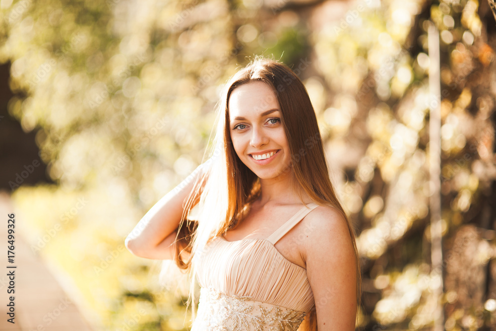 Attractive young woman with long dress enjoying her time outside in park sunset background Attractive young woman with long dress enjoying her time outside in park sunset background