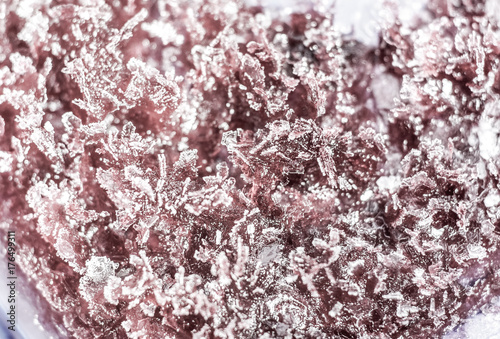 The frozen refrigerated black currant jam in a plastic container. Isolated with path top view macro photo