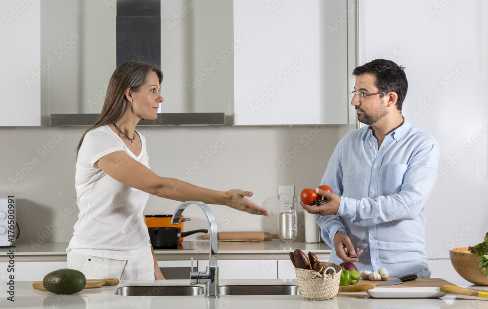 couple arguing while preparing food in a kitchen