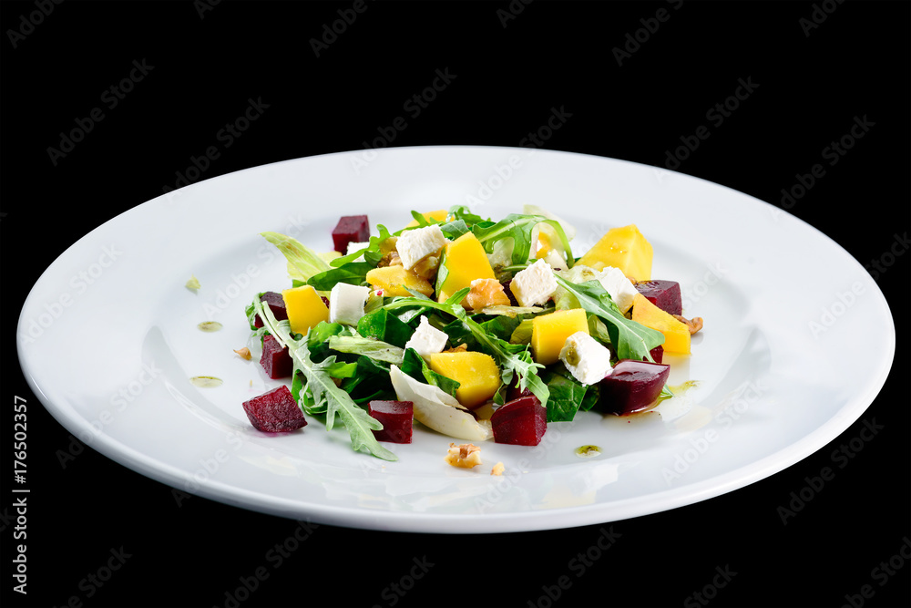 Delicious and appetizing salad with avocado, cheese and lettuce in a white plate isolated on black background. Autumn menu in an Italian restaurant. Photo for menu design