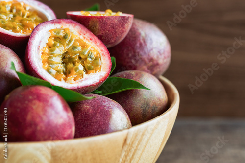 Close up fresh passion fruit in wood bowl on wood table in side view with copy space for background or wallpaper. Ripe passion fruit so delicious sweet and sour. Tropical fruit. Macro concept.