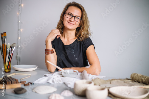 Woman painting clay pot with senior potter at workshop photo