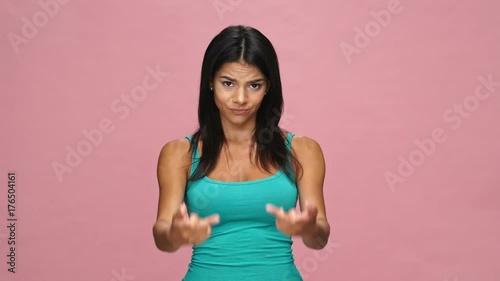 Young angry rude woman in green top showing middle fingures isolated over pink photo