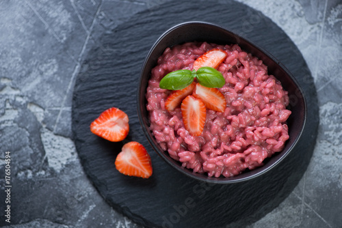 Risotto with strawberries served in a bowl on a stone slate, above view, studio shot