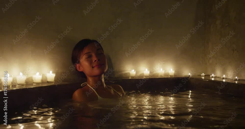 Beautiful woman relaxing in Jacuzzi. Steam is coming out from water in hot bath tub. Beauty spa is decorated with lit candles. Happy female is enjoying her vacations. Beautiful woman relaxing in Jacuzzi. Steam is coming out from water in hot bath tub. Beauty spa is decorated with lit candles. Happy female is enjoying her vacations.
