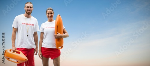 Composite image of portrait of lifeguards holding rescue buoy photo