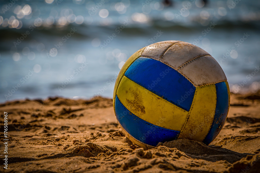 Volleyball on yellow sand on empty beach in twilight