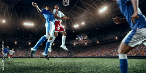 Fototapeta Naklejka Na Ścianę i Meble -  Soccer players performs an action play on a professional stadium. Two football teams fighting for the ball. Players wears unbranded sport uniform.