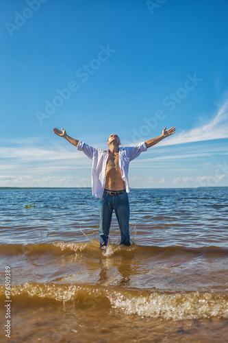 A man stands in the water and raised his hands