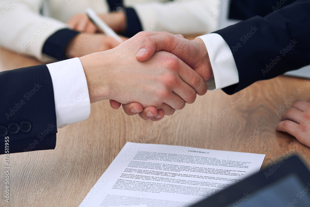 Close up of business people shaking hands at meeting or negotiation in the office. Partners are satisfied because signing contract