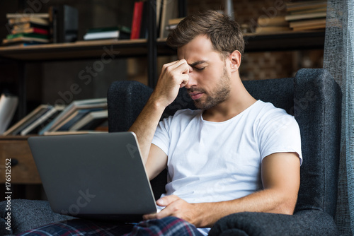 Tired man using laptop