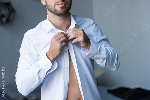 man buttoning up shirt