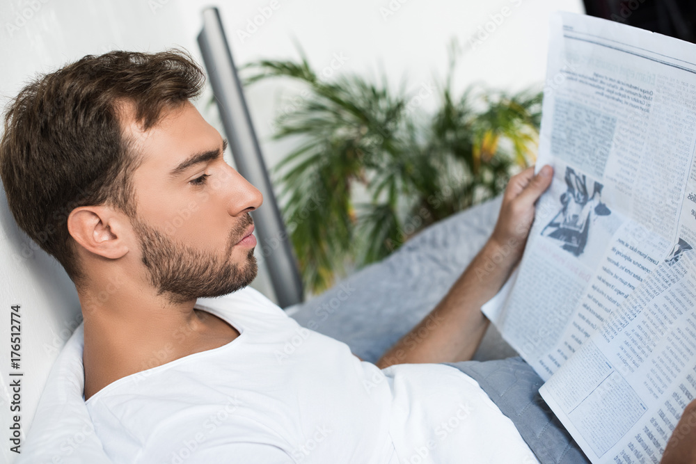 Obraz premium Man in bed reading newspaper
