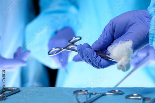 Surgeons hands holding surgical scissors and passing surgical equipment, close-up. Health care and veterinary concept