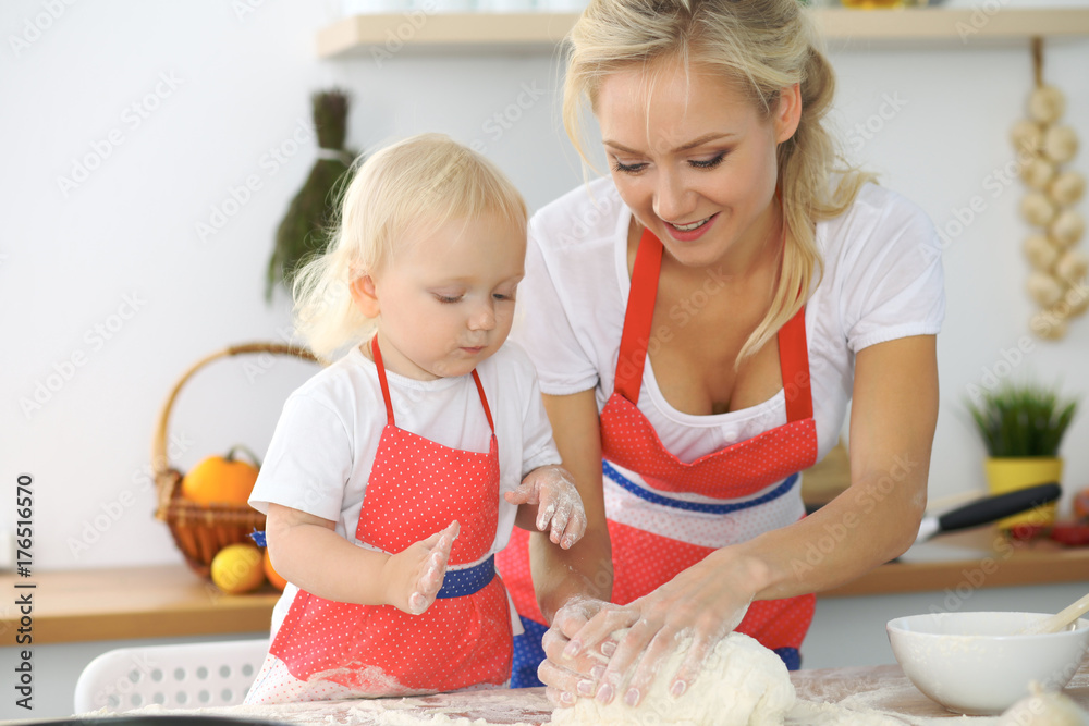Mother and little daughter are cooking in the kitchen. Spending time all together or happy family concept Mother and little daughter are cooking in the kitchen. Spending time all together or happy family concept