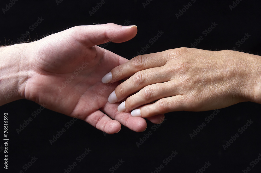 Male and female hands together on black background