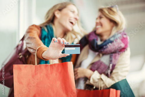 Happy woman with shopping bags holding credit card