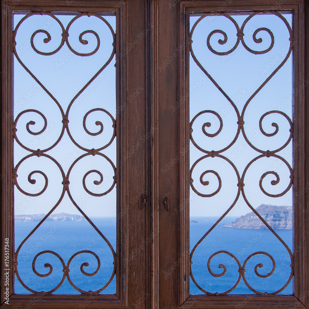 wooden door with carved pattern on the glass. Sea and blue sky on the background, Santorini Greece wooden door with carved pattern on the glass. Sea and blue sky on the background, Santorini Greece