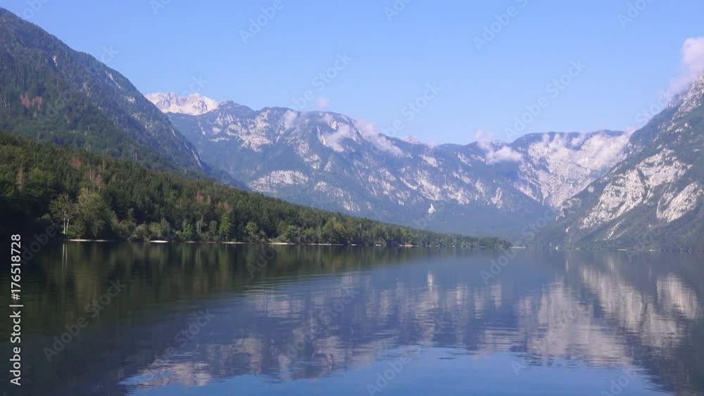 Sailing on Bohinj lake, Slovenia. Boat making waves on clear blue water surface. Summer vacation and holiday background. Sailing on Bohinj lake, Slovenia. Boat making waves on clear blue water surface. Summer vacation and holiday background.