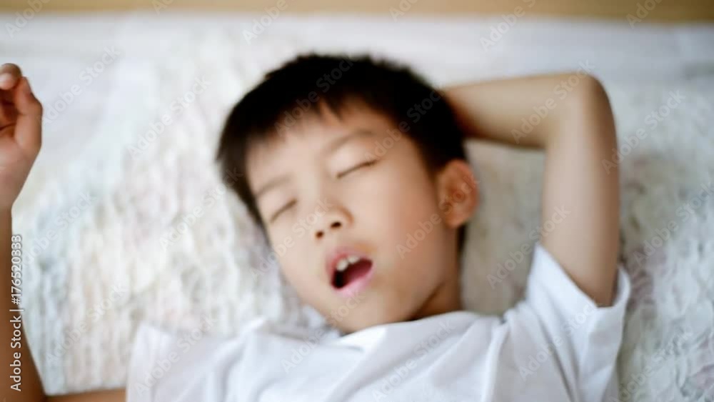 Preteen asian boy wake up and yawing in a white bed room in a morning. Preteen asian boy wake up and yawing in a white bed room in a morning.