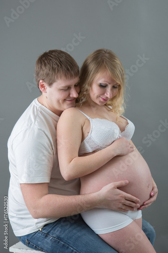 Beautiful pregnant couple in love on the background.Hands of husband on the tummy of his pregnant wife. Young man tenderly stroked pregnant belly of his wife. Husband kissing pregnant belly.