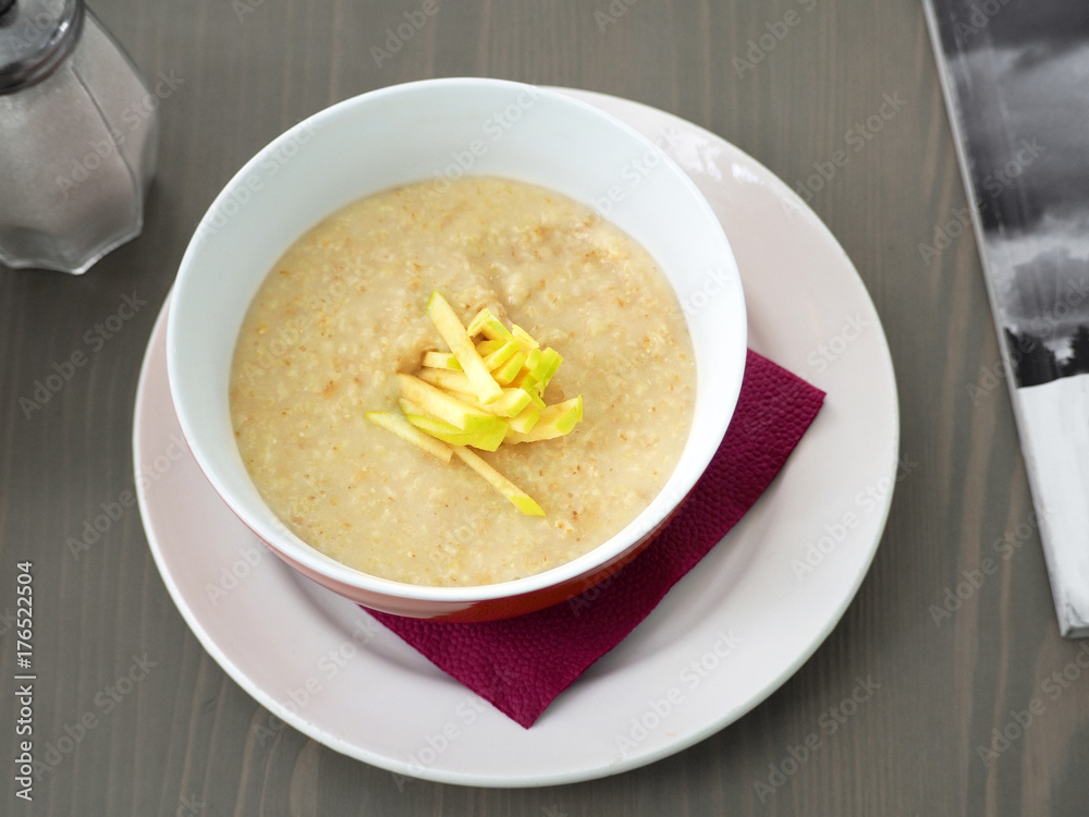 Oatmeal porridge with cut slices of apples in a deep plate on a wooden table. A good and useful diet breakfast for a healthy lifestyle Oatmeal porridge with cut slices of apples in a deep plate on a wooden table. A good and useful diet breakfast for a healthy lifestyle