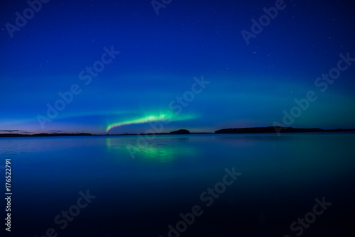 Northern lights dancing over calm lake in Farnebofjarden national park in Sweden. © Conny Sjostrom