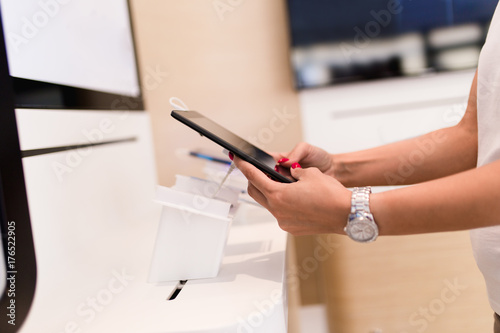 Close up shot of woman shopping tablet. She is standing in mobile and tablet shop and choosing next model for her. 