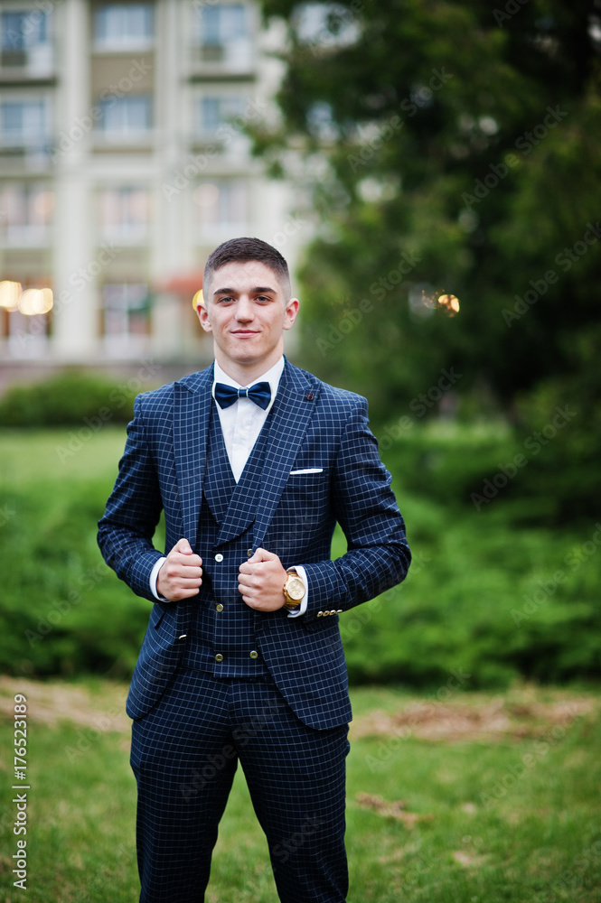 Portrait of a handsome young guy dressed in cool suit posing on the lawn on his prom day. Portrait of a handsome young guy dressed in cool suit posing on the lawn on his prom day.