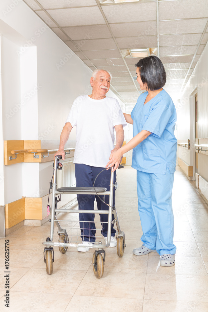 Obraz premium Nurse helping elderly man with walker in hospital