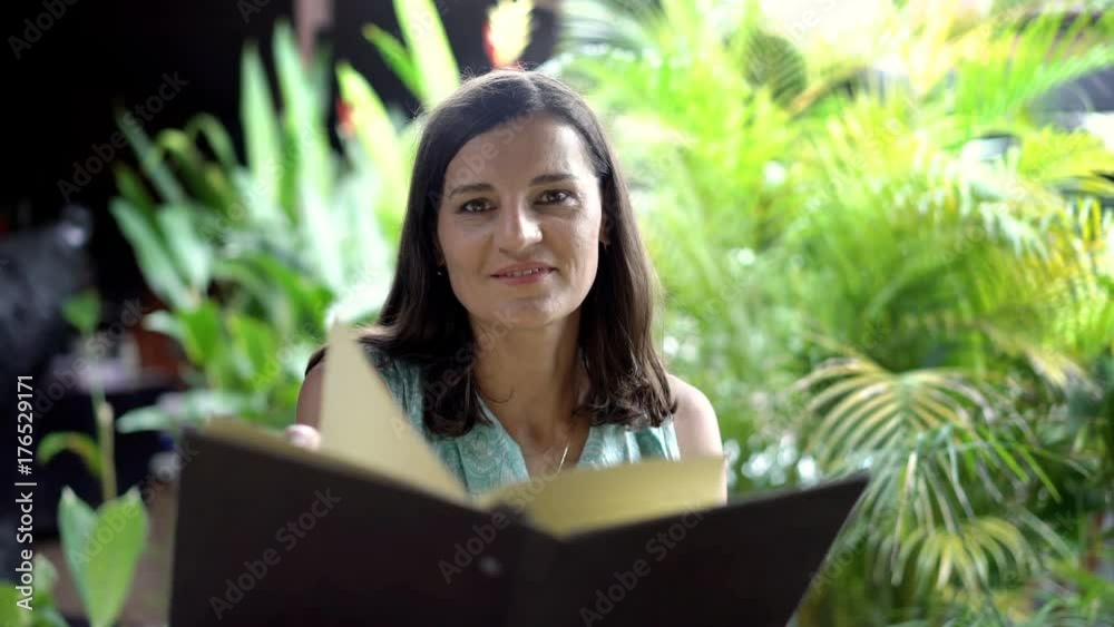 Attractive woman reading menu in exotic restaurant and smiling to the camera, steadycam shot
Attractive woman reading menu in exotic restaurant and smiling to the camera, steadycam shot