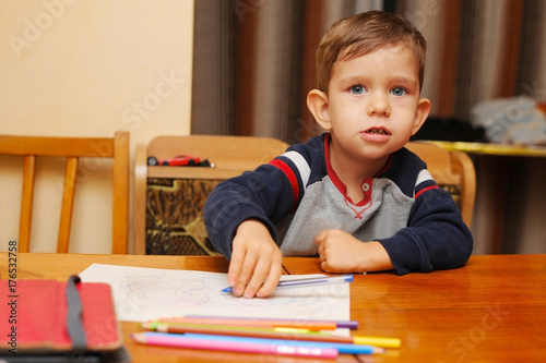 Little boy paints by pen on a piece of paper