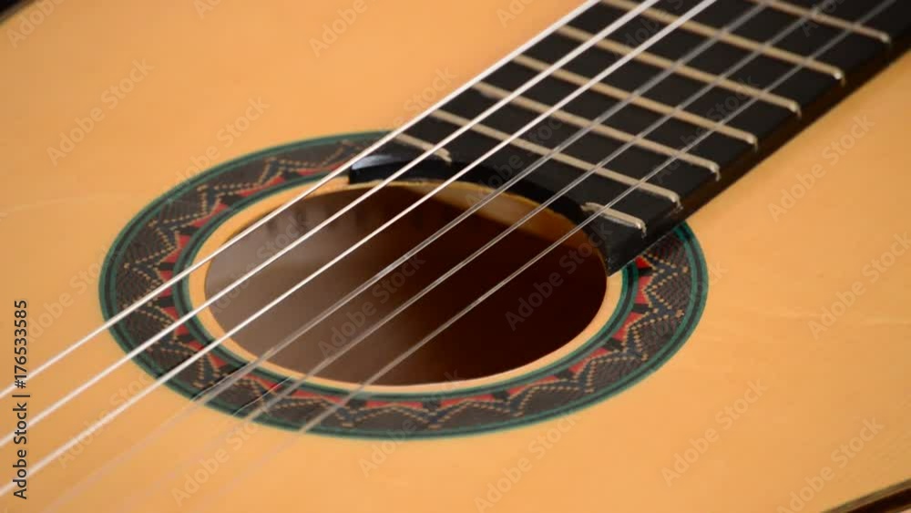 Detail of mouth, strings, frets, body and bridge of spanish classic guitar with red mouth rotating at black background