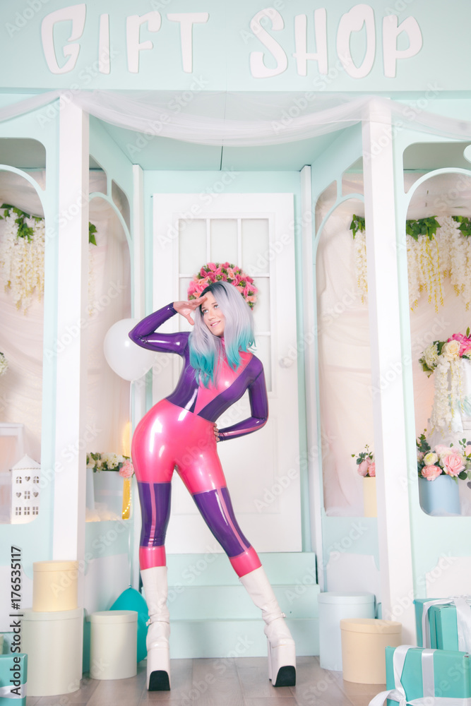 Fotka „pretty anime girl wearing latex rubber doll catsuit and posing near  cute white gift shop with air ballons and presents and gifts for christmas  and new year“ ze služby Stock
