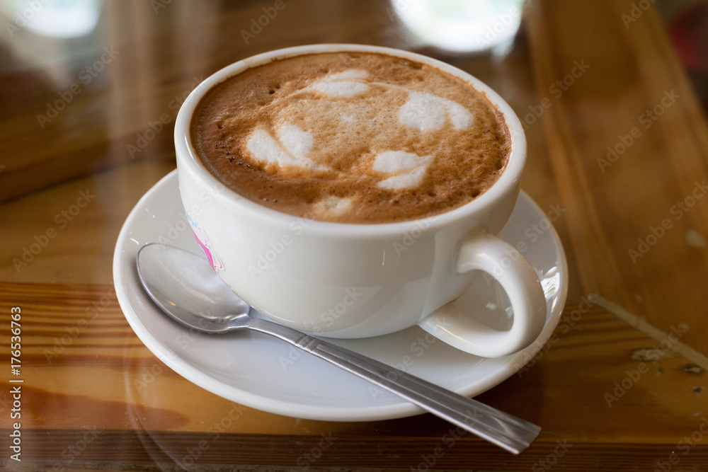 A cup of coffee with latte art on wooden table. A cup of coffee with latte art on wooden table.