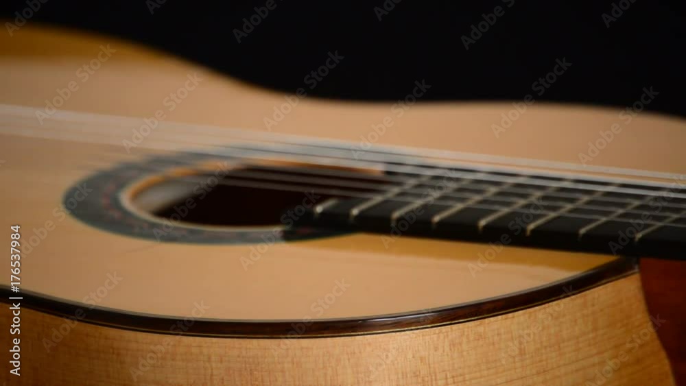 Detail of mouth, strings, frets, body of spanish classic guitar with red mouth rotating at black background