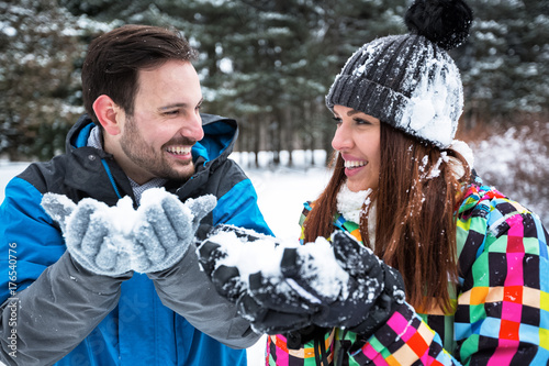 Young happy couple holding snow in hands and smiling together
