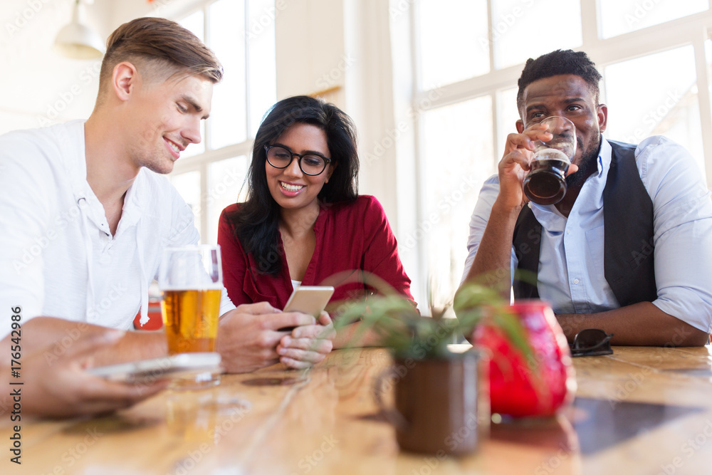 happy friends with smartphone drinking beer at bar