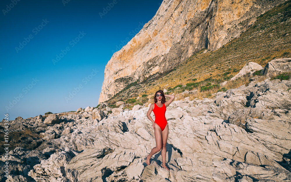 Fashion portrait of a young beautiful girl in red bikini in sicilian sea coast