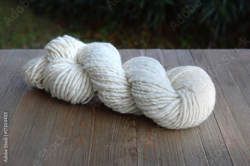 This is a photo of a skein of natural colored hand spun yarn on a wood table.