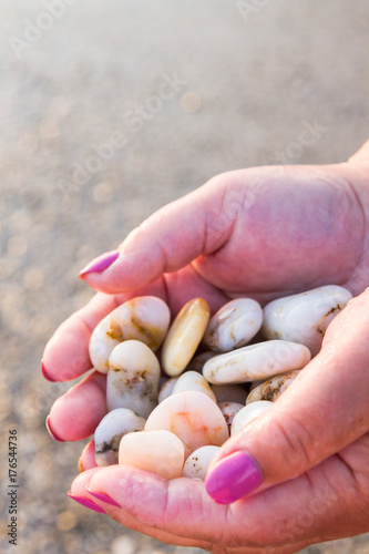 Sea stones in hands on the beach at sunset