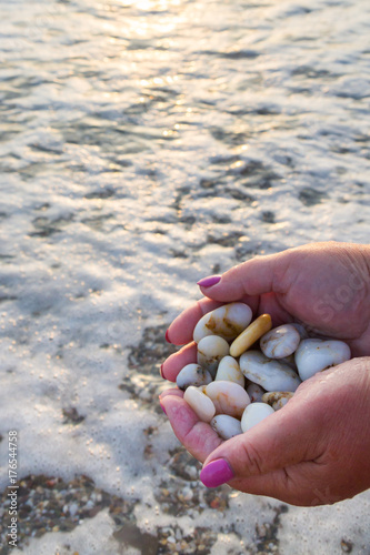 Sea stones in hands on the beach at sunset