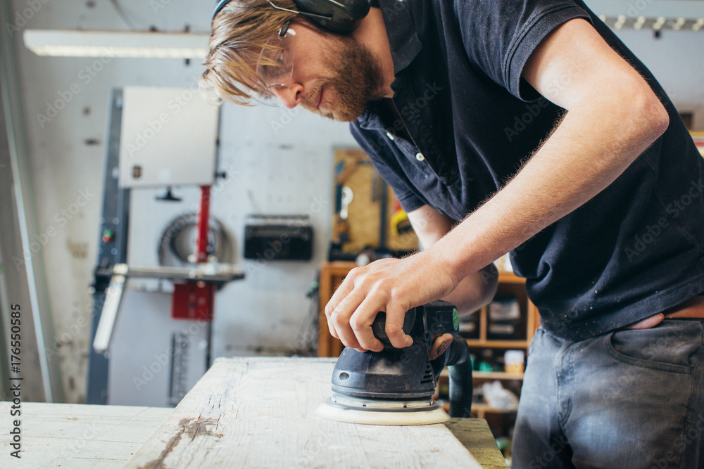 Carpentry Young Carpenter Wearing Safety Glasses Sanding Wood Plank