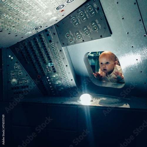 A baby looking through the window of an Apollo Space craft replica. photo