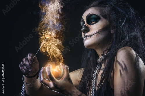 Zombie death voodoo scary witch girl, halloween concept, casting fire spells with her wand photo