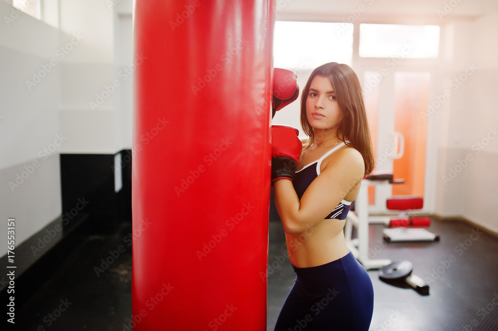 Young beautiful woman, wear on boxing gloves doing exercises and working hard in gym and enjoying her training process.