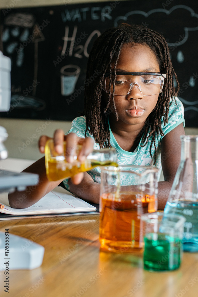 Girl pouring liquid in a beaker Girl pouring liquid in a beaker